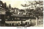 Foto do antigo prdio do Colgio Carlos Gomes, So Joo do Caiu, j em seu terreno prprio. O prdio todo em madeira, os alunos cantando o hino nacional em frente  bandeira nacional, em 1968. <br /><br /> Colaborao: Deivid da Silva Amaral <br /><br /> <strong>*A imagem disponibilizada  de responsabilidade do colaborador.</strong>